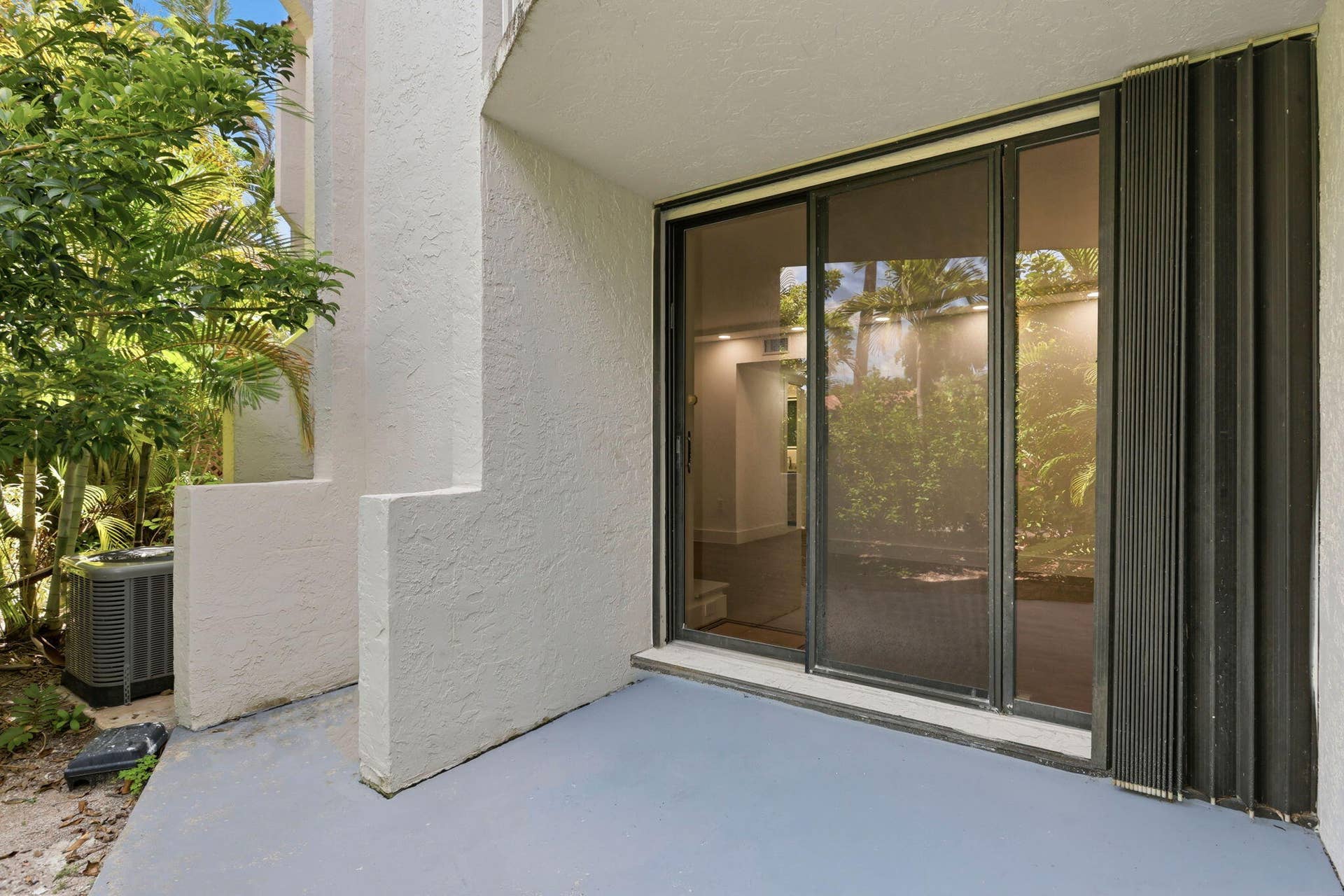 1222 Hillsboro Mile, #15, Hillsboro Beach, FL 33062 Patio with sliding glass doors, accordion hurricane shutters, and an air conditioning unit
