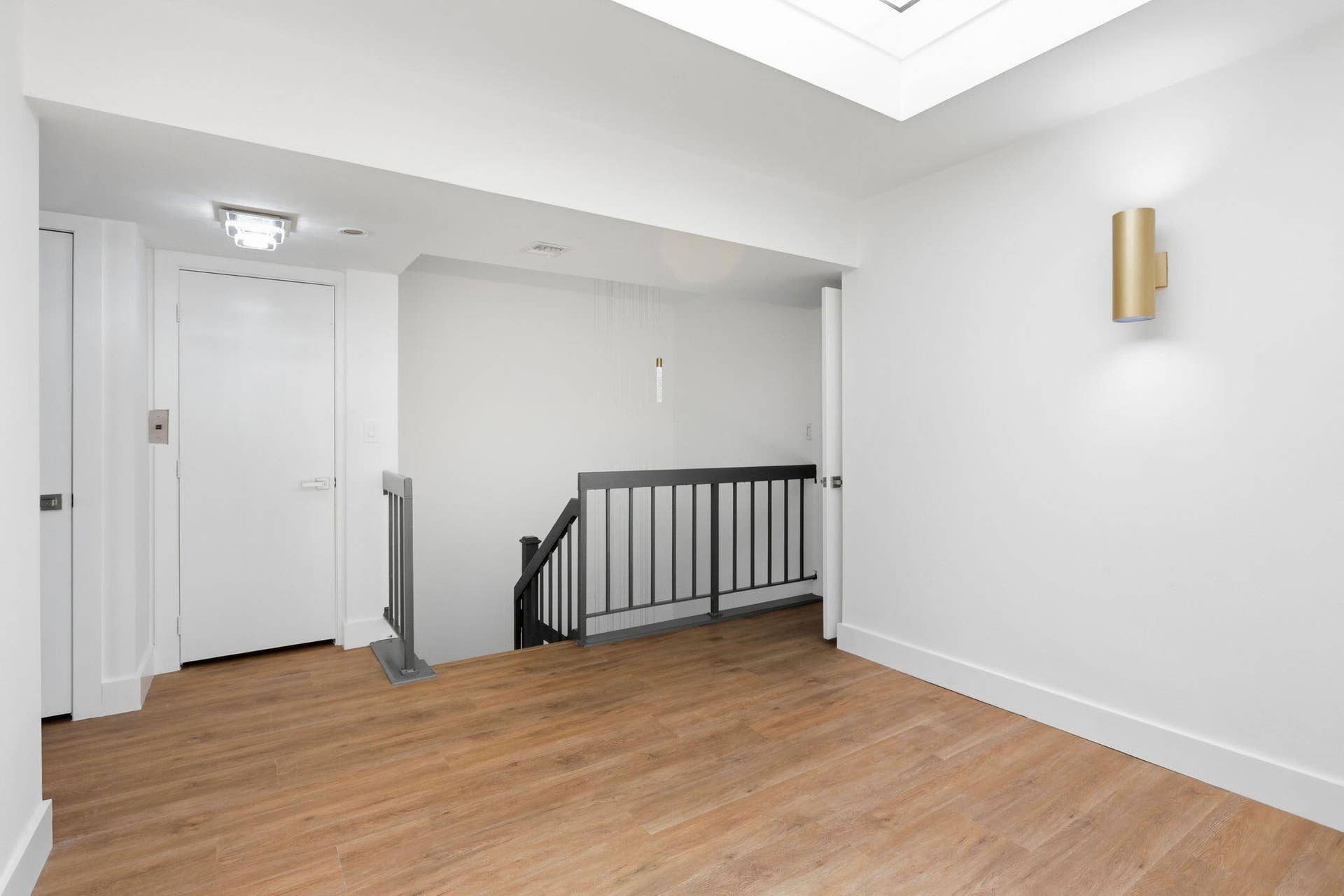 1222 Hillsboro Mile, #15, Hillsboro Beach, FL 33062 Wood-finish flooring, white walls, and a contemporary brass wall sconce