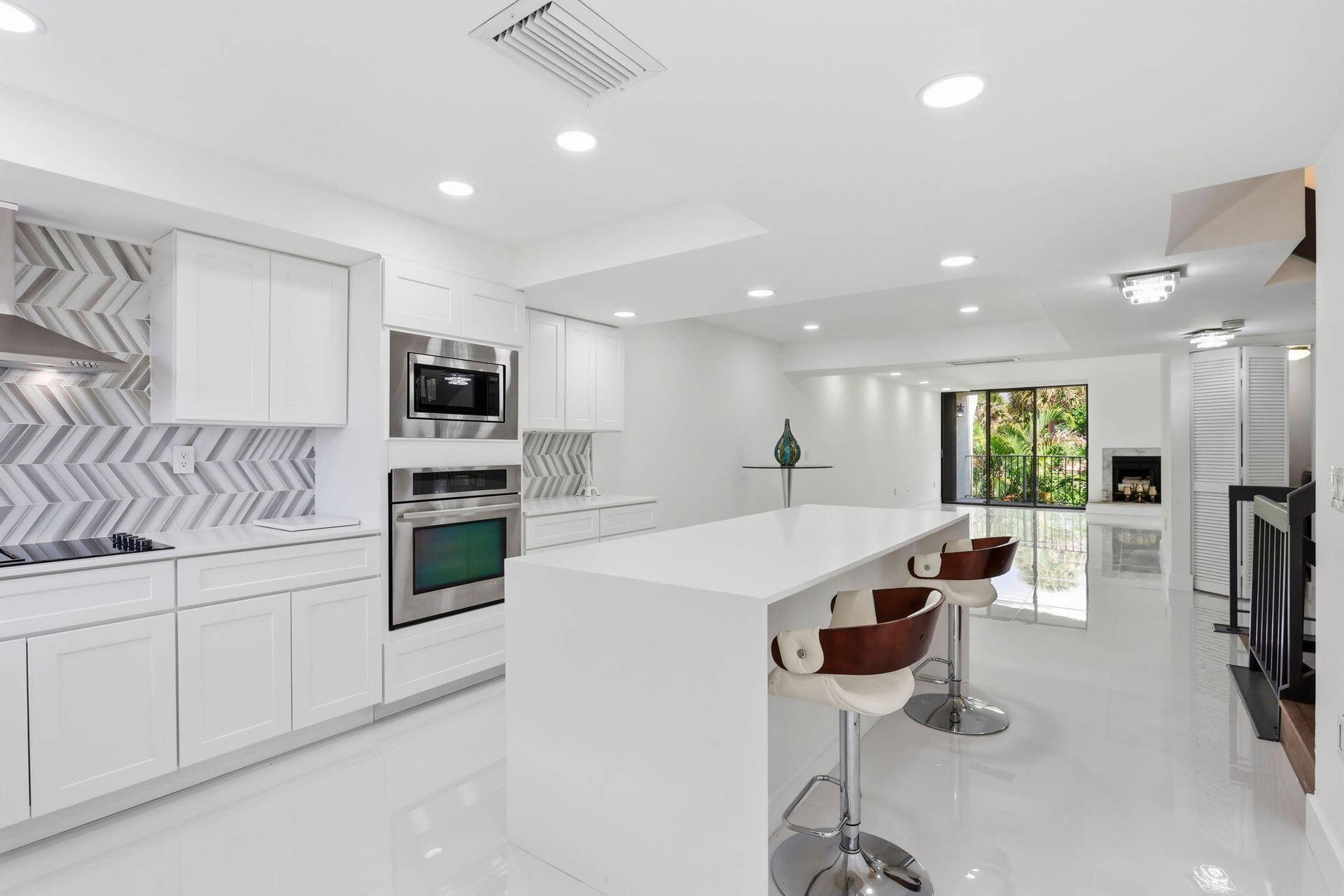 1222 Hillsboro Mile, #15, Hillsboro Beach, FL 33062 White shaker cabinetry, stainless steel appliances, herringbone tile backsplash, recessed lighting, and a kitchen island with a white countertop