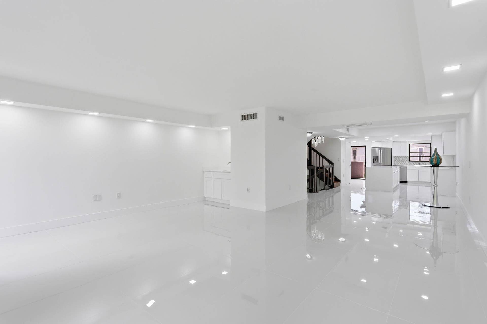 Open-concept living space featuring high-gloss tile flooring, recessed lighting, and a white cabinet with a sink