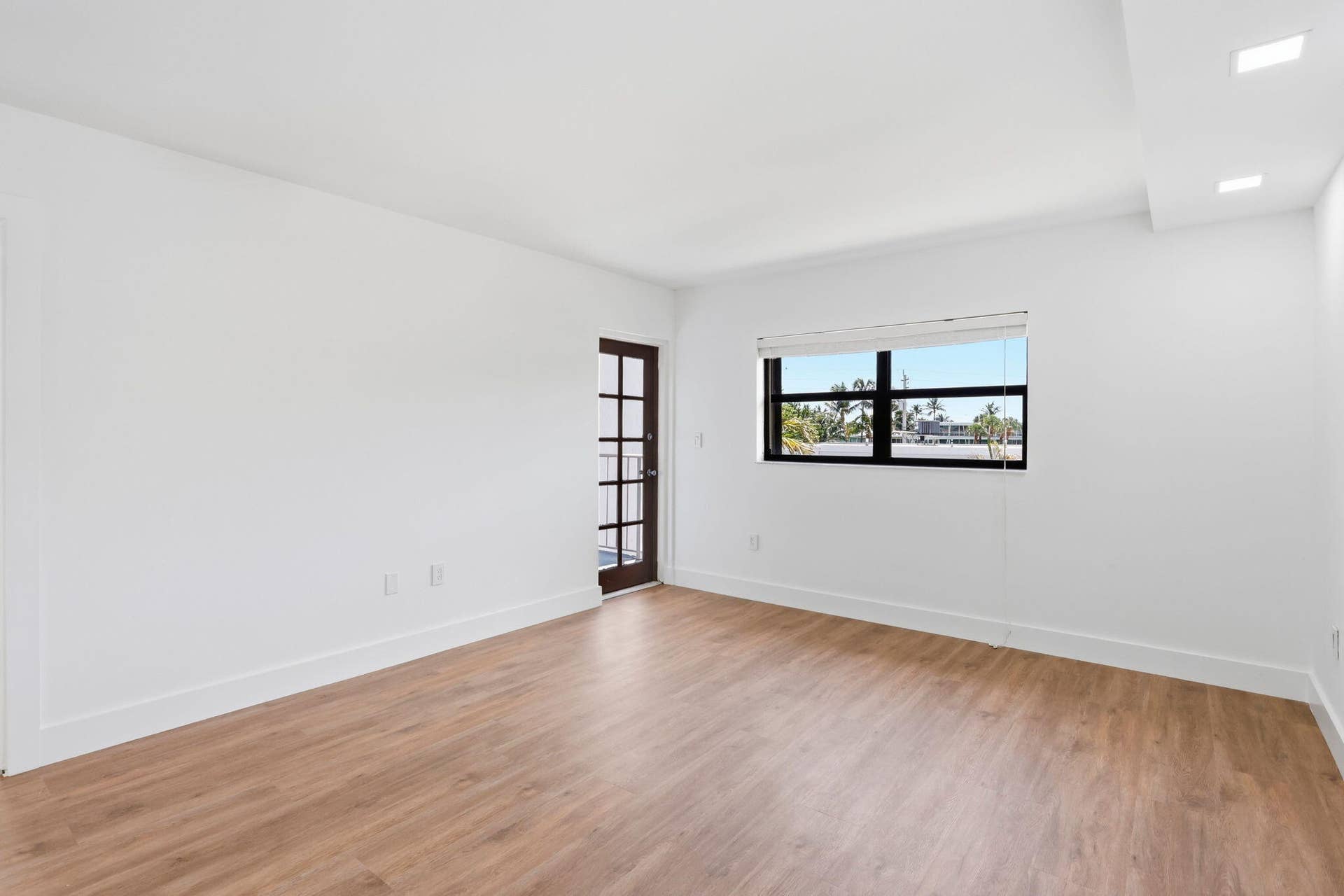 Wood-finish flooring, white painted walls, recessed lighting, French-style door, and a horizontal window with blinds