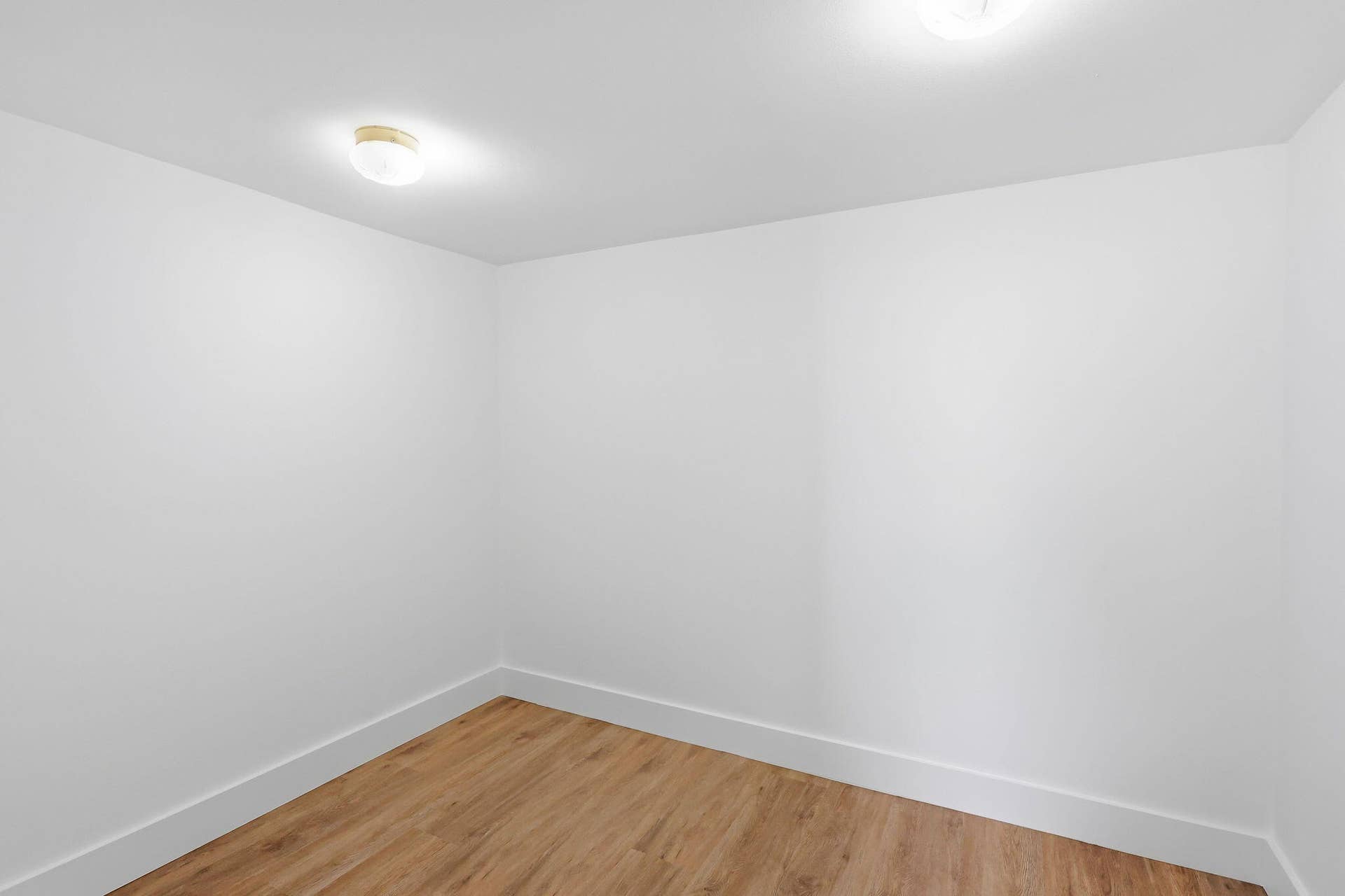 Recessed ceiling lighting, wood-finish flooring, and white walls