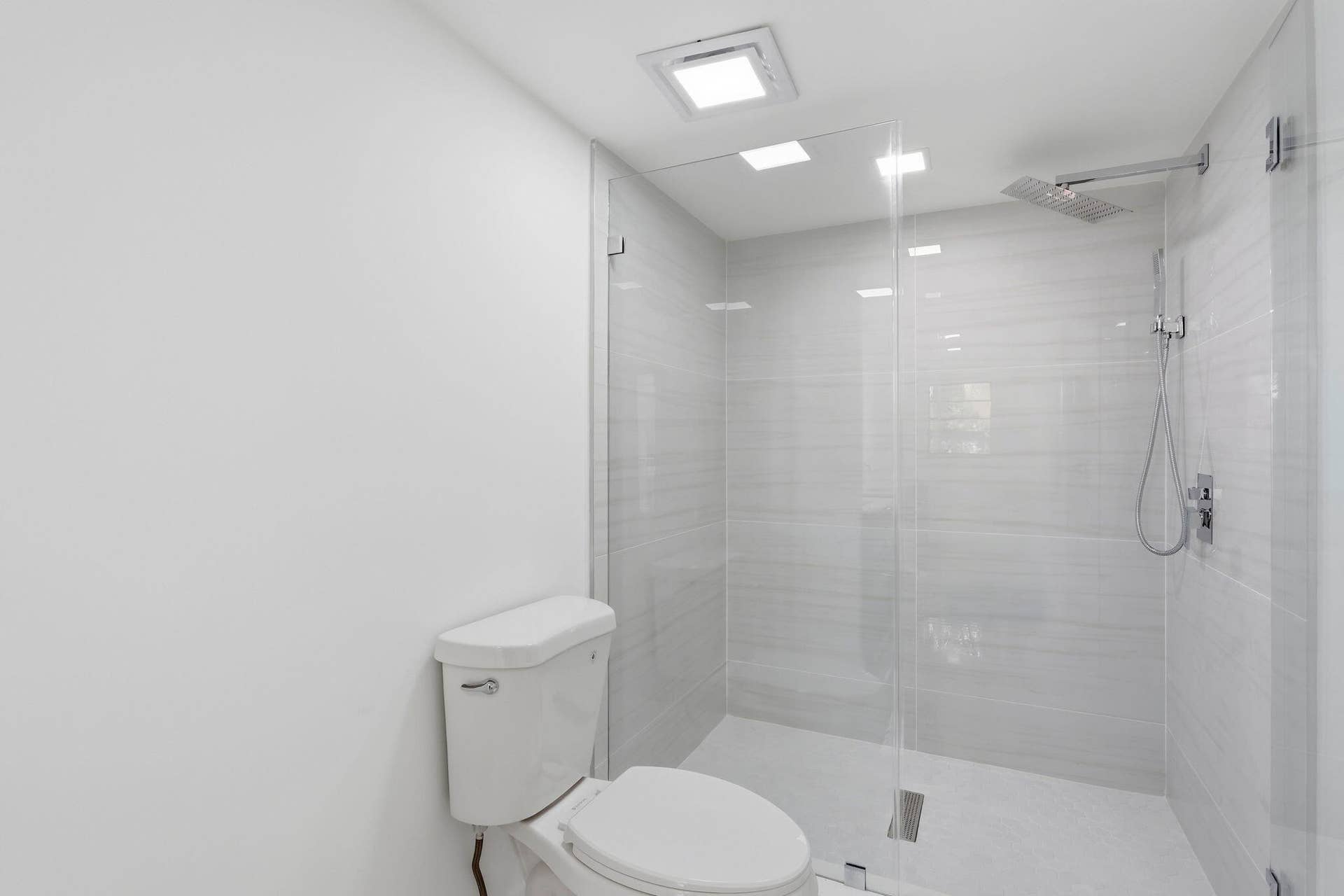 Walk-in shower with clear glass enclosure, tiled walls, and a rainfall showerhead