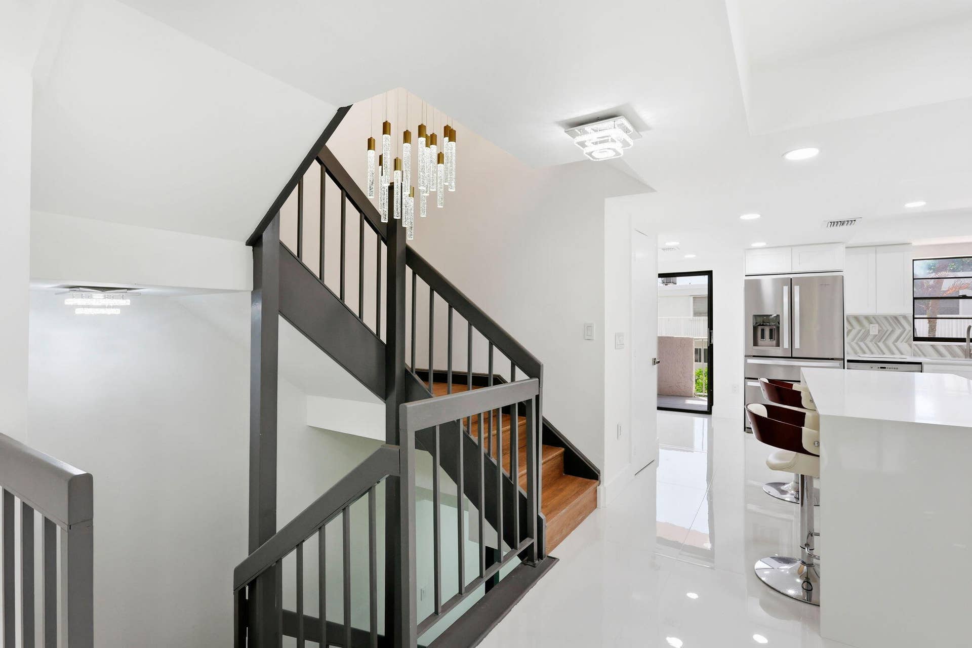 Modern kitchen featuring stainless steel appliances, white cabinetry, and beatifyl staircase