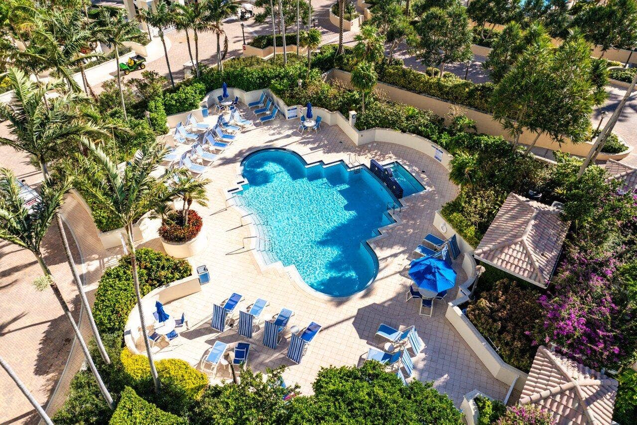 3700 S OCEAN Boulevard, #404, Highland Beach, FL 33487 Resort-style pool area with a freeform swimming pool, integrated spa, paver decking, lush landscaping, and cabana structure