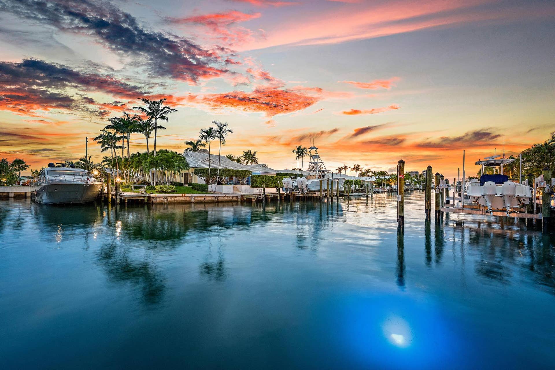 Waterfront property with extensive boat docks, mature palm trees, and a manicured lawn