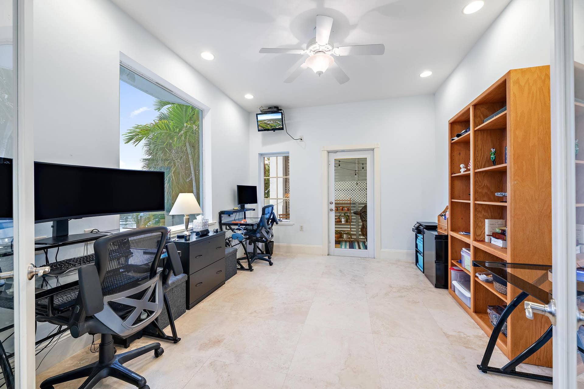 Recessed lighting, ceiling fan, built-in shelving, glass-paned door, and large window