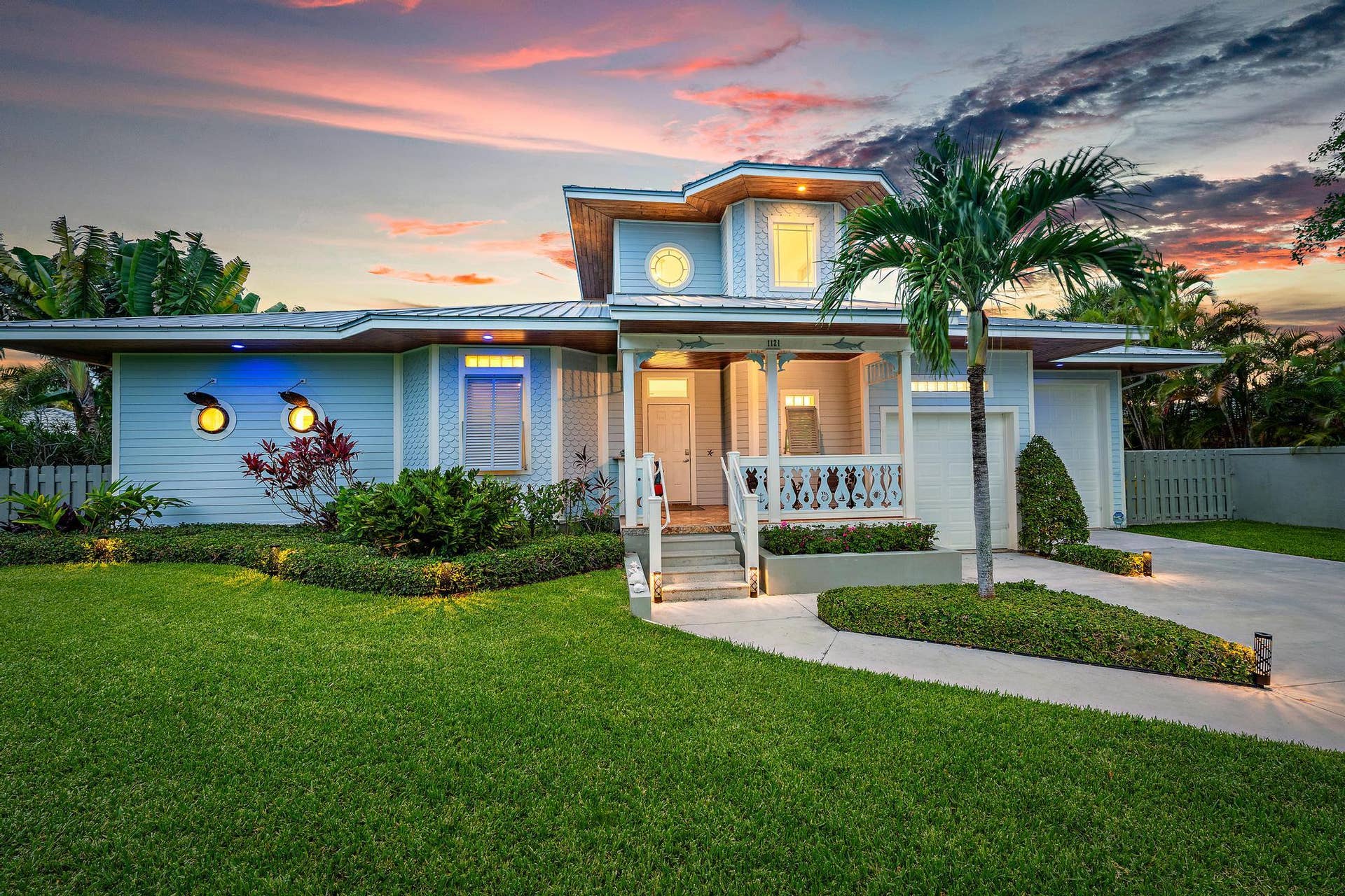 Contemporary exterior with multi-level roofline, prominent front porch, attached garage, and mature palm tree