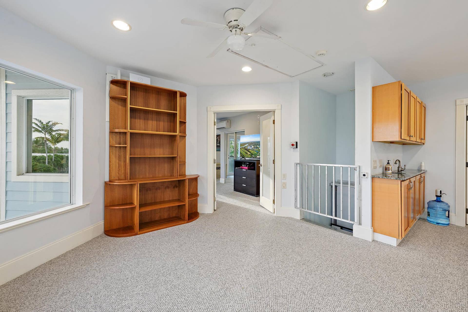 Built-in wood shelving, a ceiling fan with integrated lighting, recessed ceiling lighting, a built-in wet bar with cabinetry, and a large window