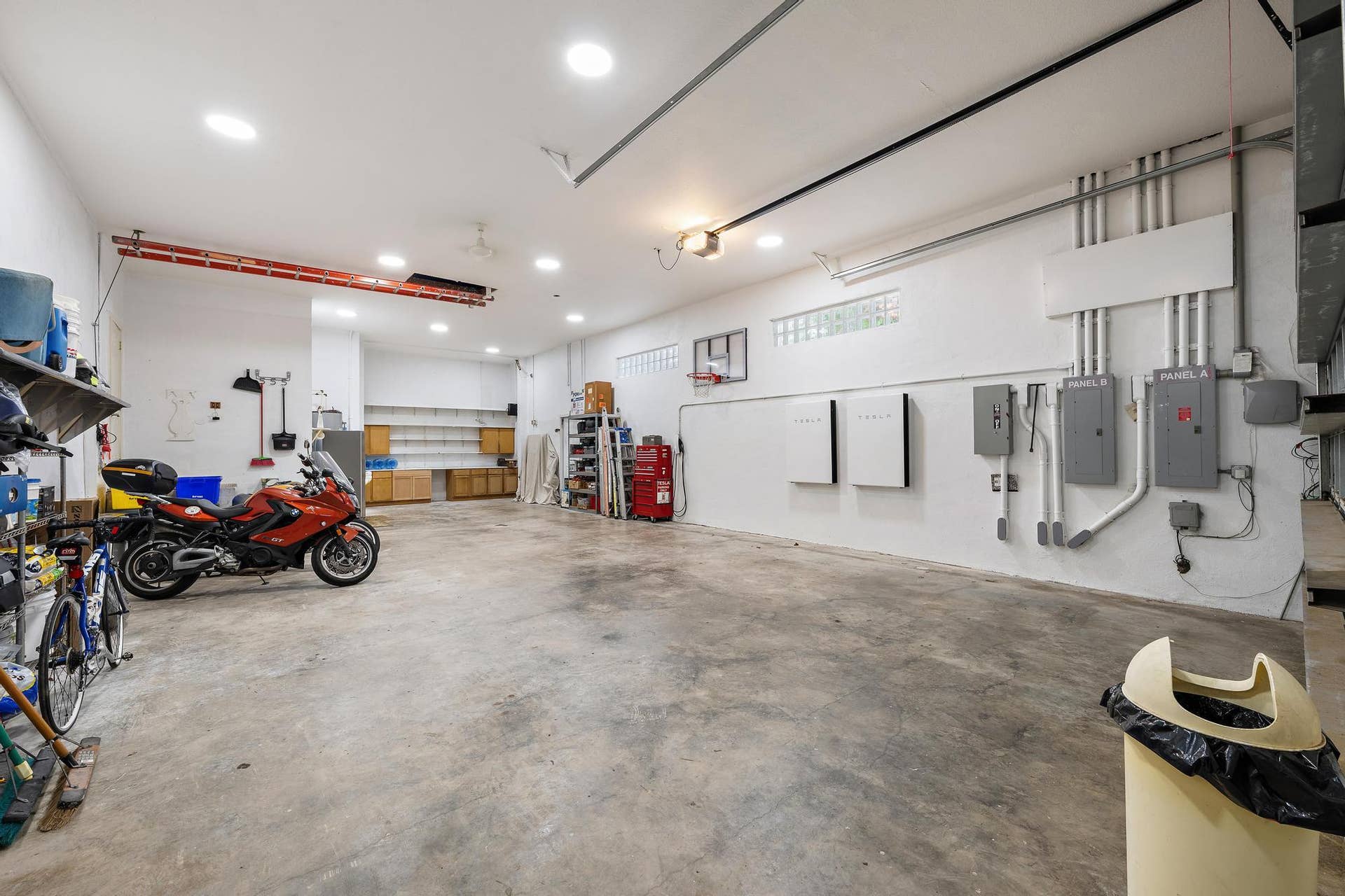 Spacious garage featuring concrete flooring, recessed lighting, built-in cabinetry, and integrated electrical panels