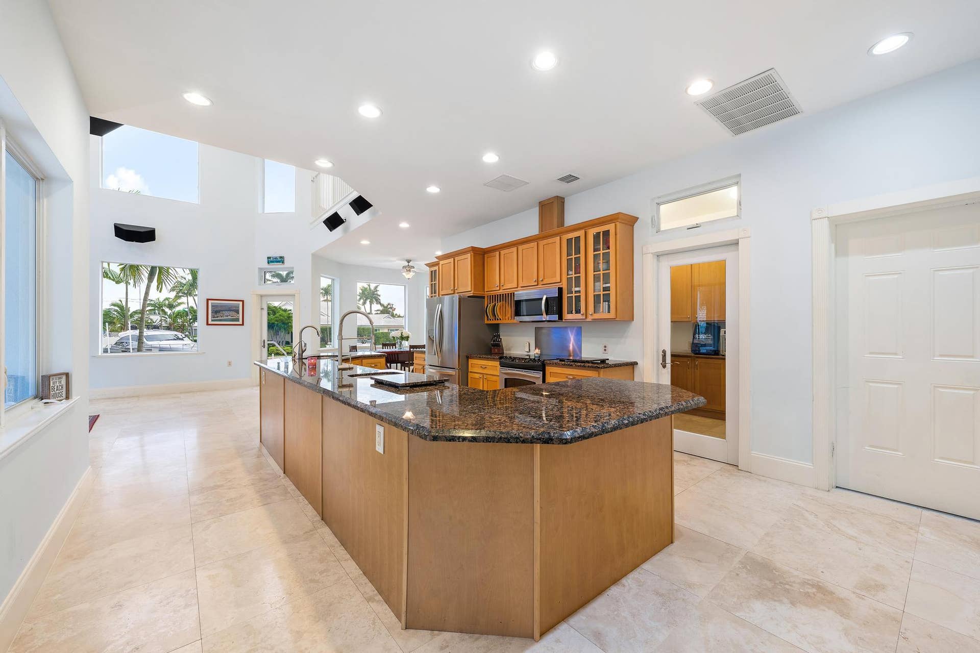 Kitchen featuring a large island with granite countertop, wood cabinetry, stainless steel appliances, and recessed lighting
