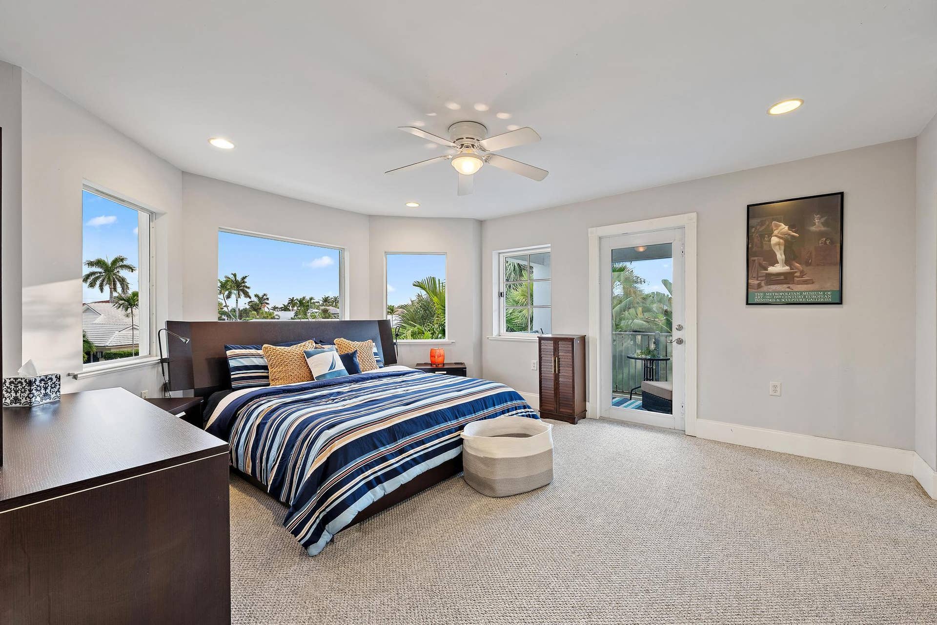 Recessed lighting, ceiling fan, multiple windows, and a glass-paneled door opening to an outdoor area