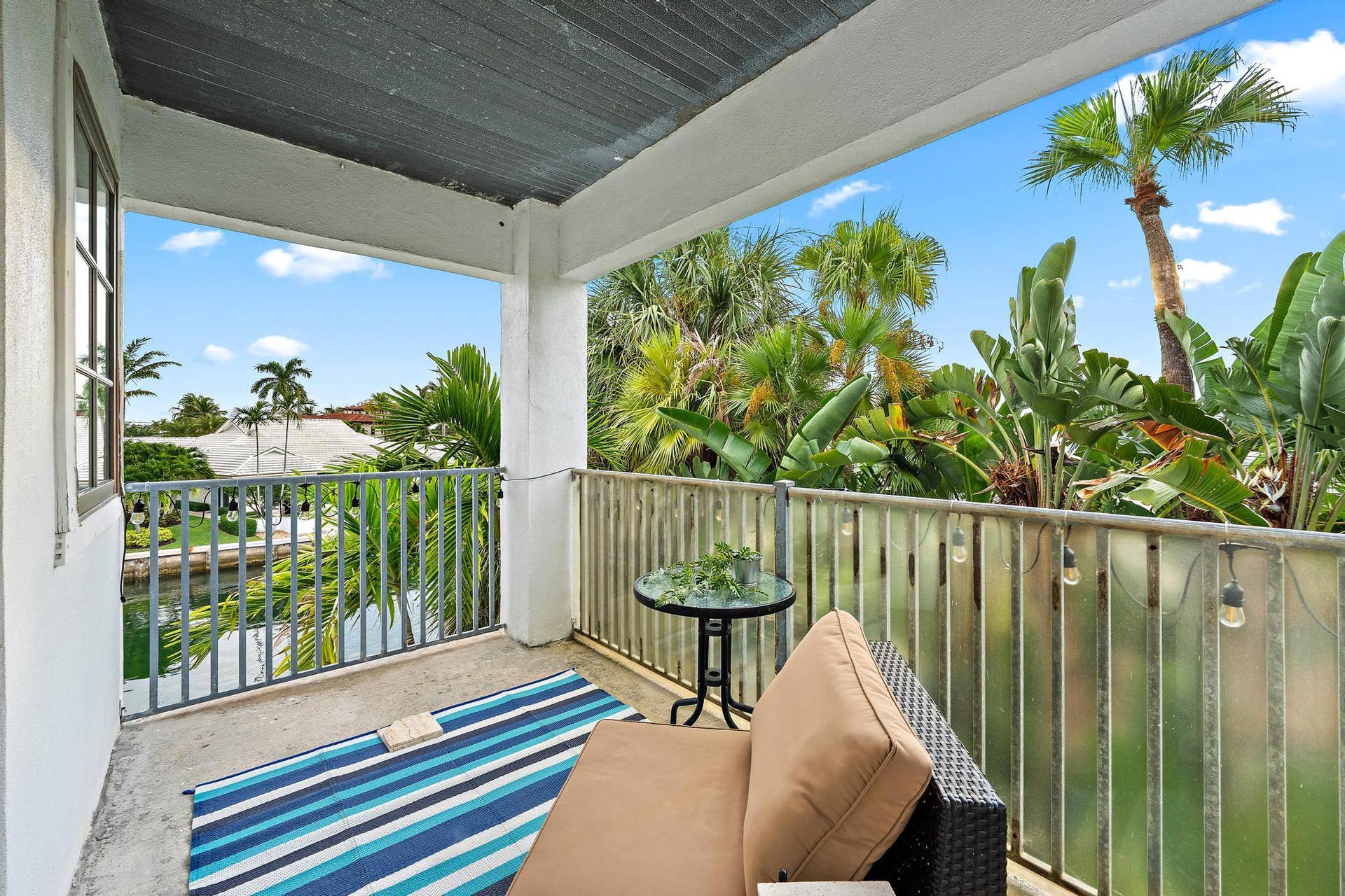 Outdoor balcony with a sturdy railing, concrete flooring, and an exterior window