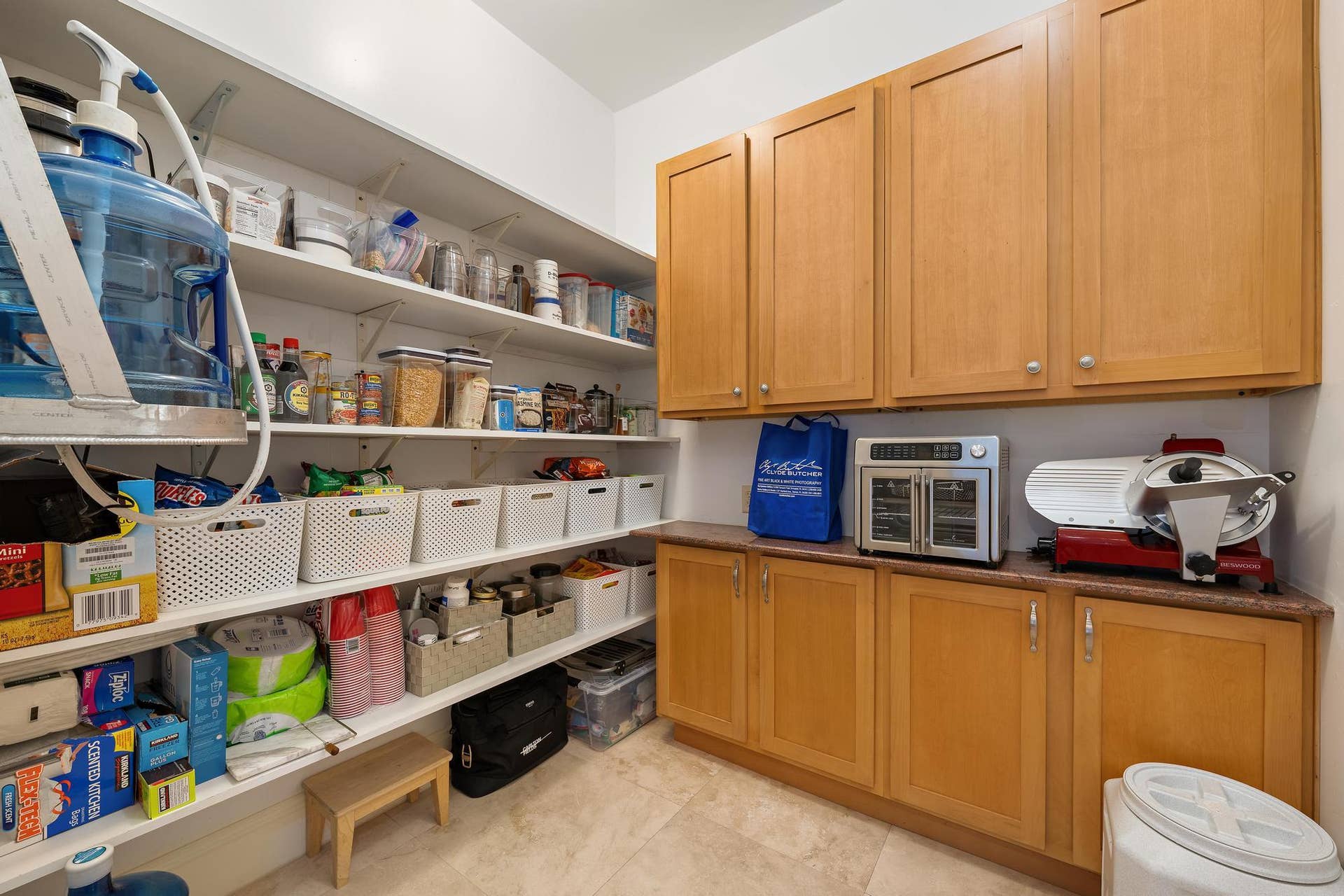 Integrated pantry storage featuring a combination of open shelving, upper cabinetry, lower cabinetry, and a countertop surface