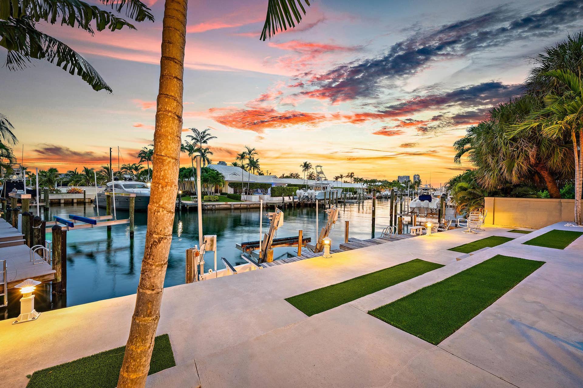 Waterfront property featuring dock access, integrated lighting, and palm trees
