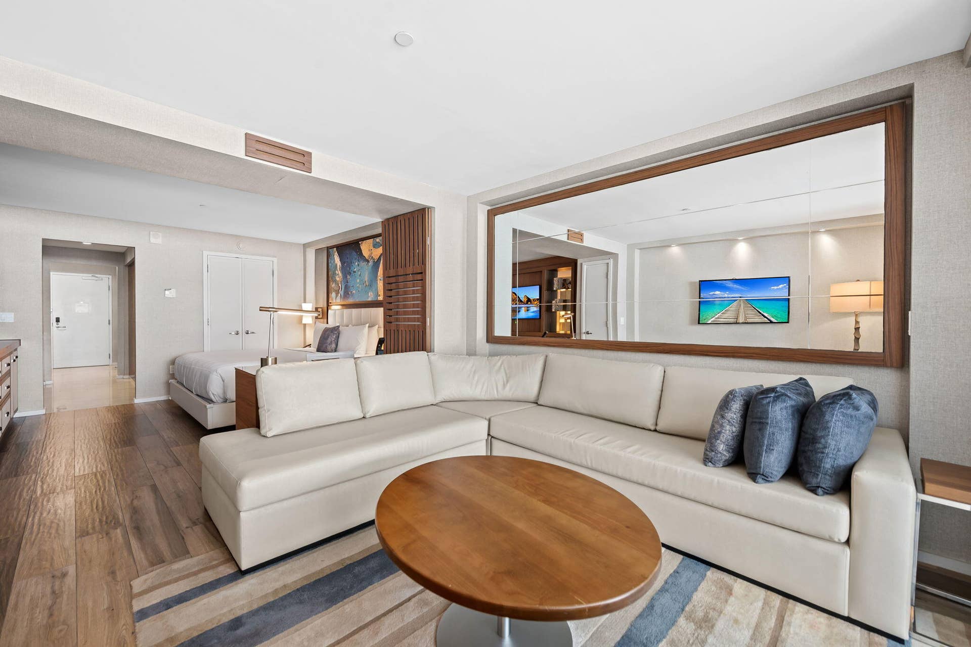 Wood-finish flooring throughout, integrated ceiling lighting, and a large wall-mounted mirror with wood framing
