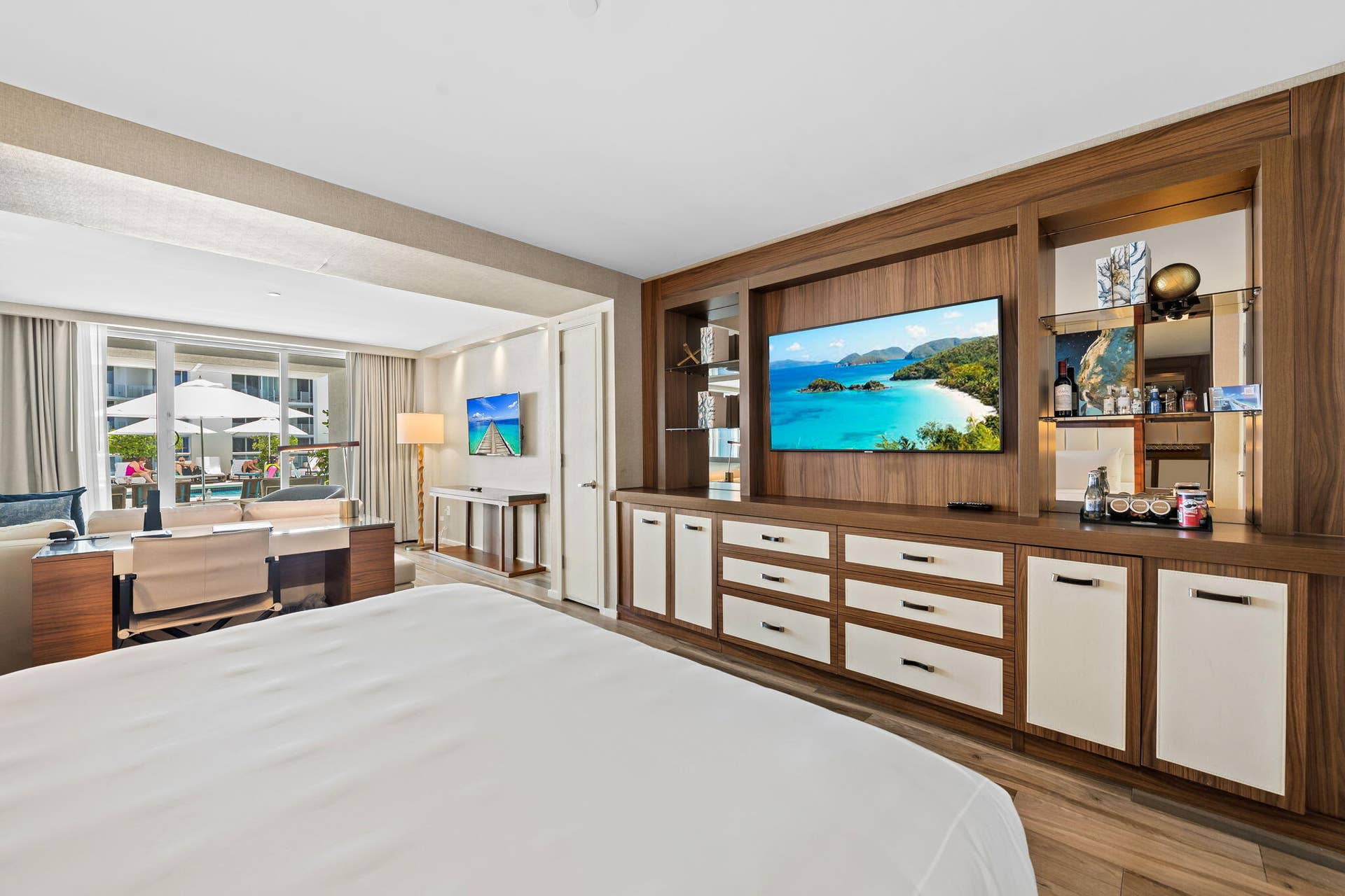 Wood-finish flooring, built-in entertainment center, integrated storage drawers, wet bar with mirrored backsplash, and expansive glass doors