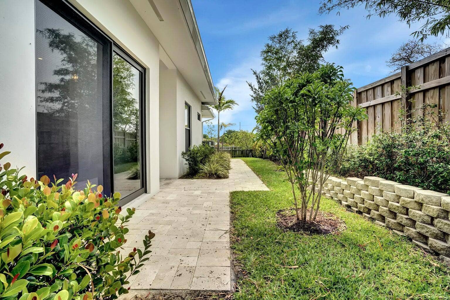 2517 Oceanview Avenue E, Delray Beach, Delray Beach, FL 33444 Modern exterior with large sliding glass doors, a stone-finish patio, and a manicured lawn