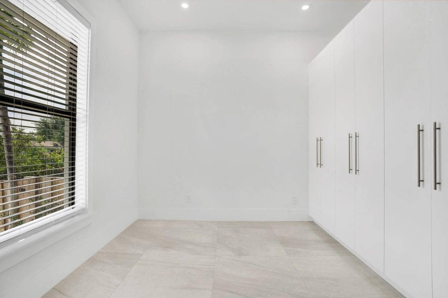 2517 Oceanview Avenue E, Delray Beach, Delray Beach, FL 33444 Recessed lighting, large window with horizontal blinds, built-in white cabinetry with bar pull hardware, and light-toned tile flooring