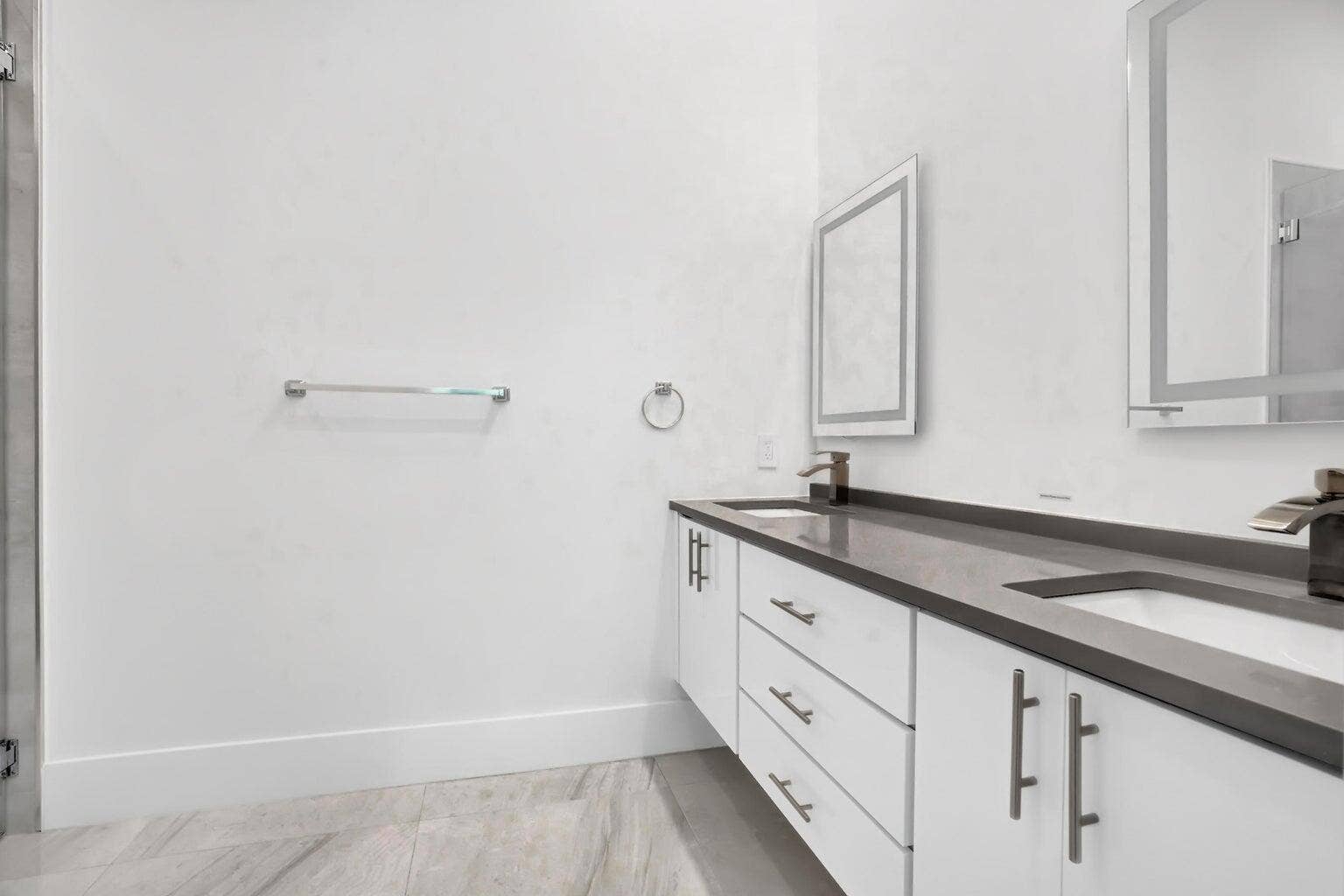 2517 Oceanview Avenue E, Delray Beach, Delray Beach, FL 33444 Dual floating vanities with integrated sinks, dark countertops, white cabinetry, and wall-mounted mirrors