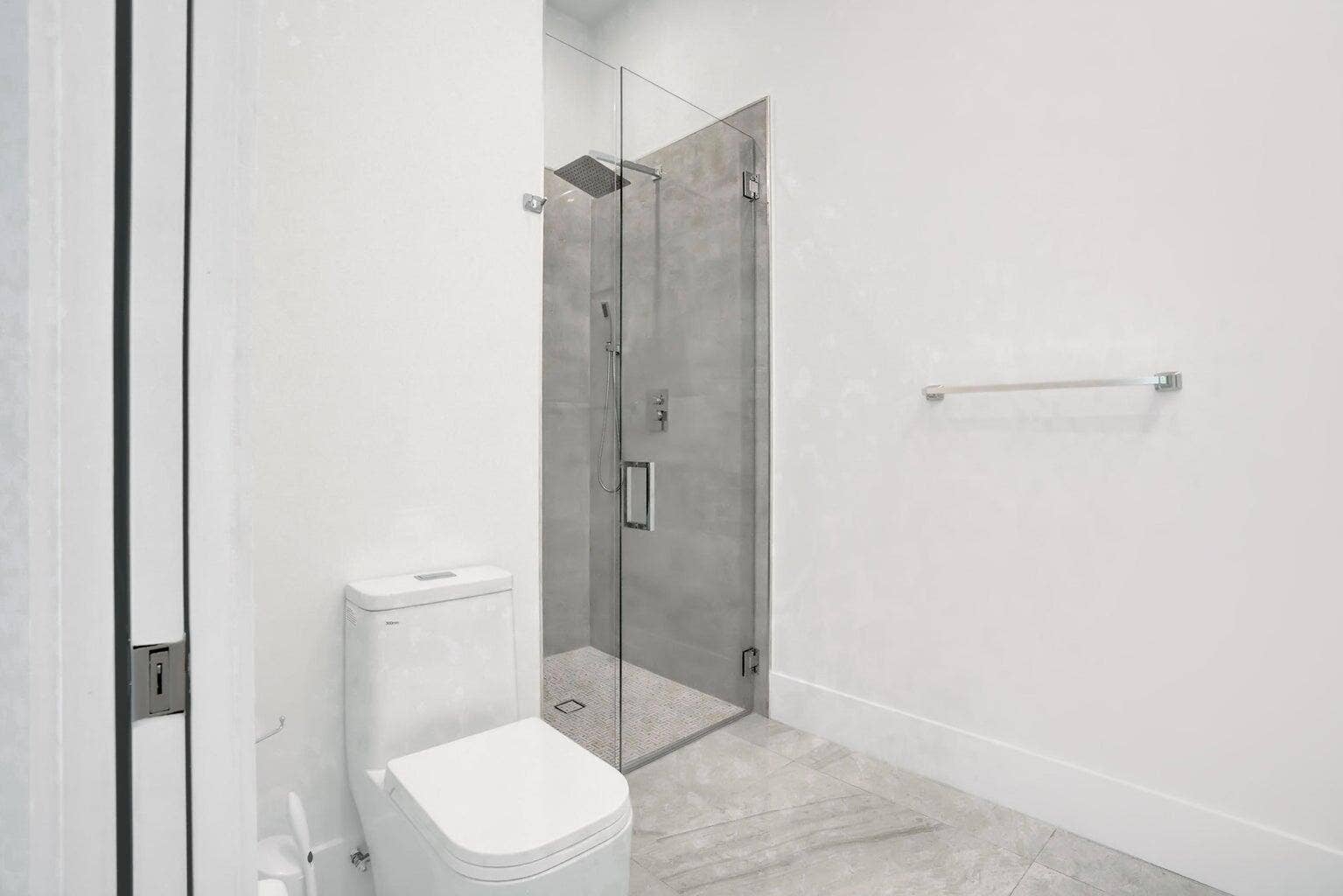 2517 Oceanview Avenue E, Delray Beach, Delray Beach, FL 33444 Contemporary bathroom featuring a frameless glass shower enclosure, a rainfall showerhead, and light-toned wall and floor tile