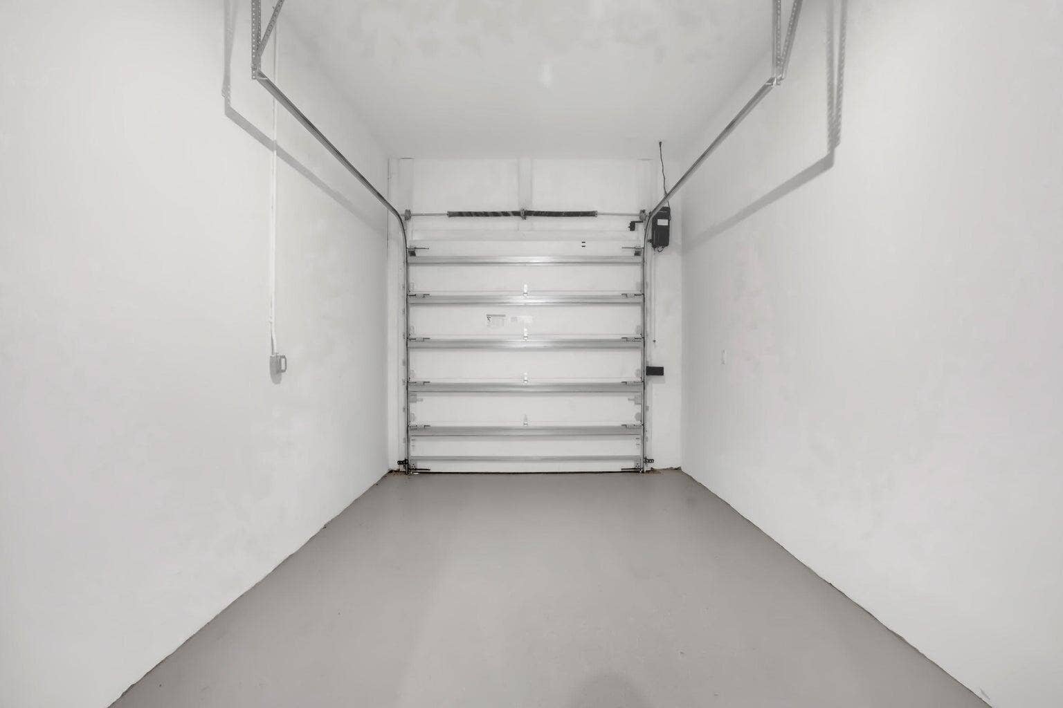 2517 Oceanview Avenue E, Delray Beach, Delray Beach, FL 33444 Enclosed garage space featuring a roll-up door, white walls, and a gray floor