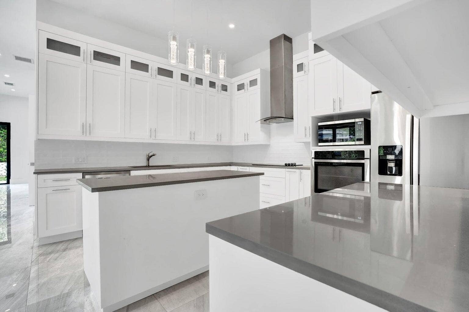 2517 Oceanview Avenue E, Delray Beach, Delray Beach, FL 33444 White shaker cabinetry with upper glass-front accents, dual kitchen islands, and integrated stainless steel appliances