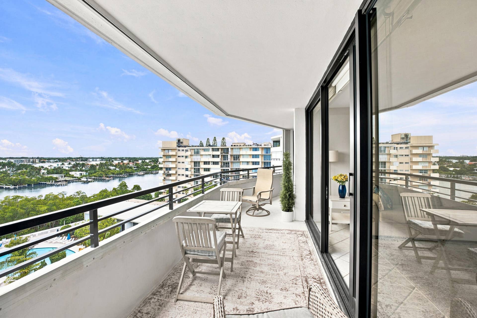 3589 S Ocean Boulevard, #808, South Palm Beach, FL 33480 Expansive balcony featuring a water backdrop with distant buildings, a black metal railing, and large sliding glass doors