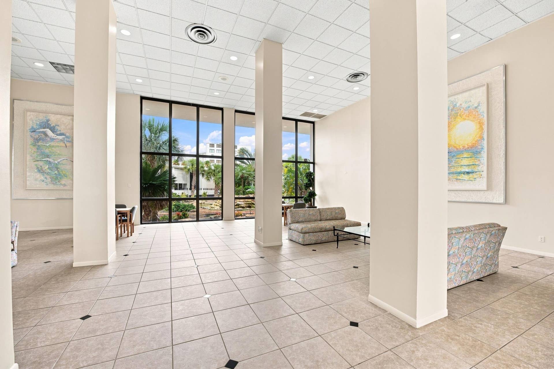3589 S Ocean Boulevard, #808, South Palm Beach, FL 33480 Spacious ground floor lobby greets you featuring light-toned tile flooring with dark accent inlays, multiple structural columns, and large floor-to-ceiling windows