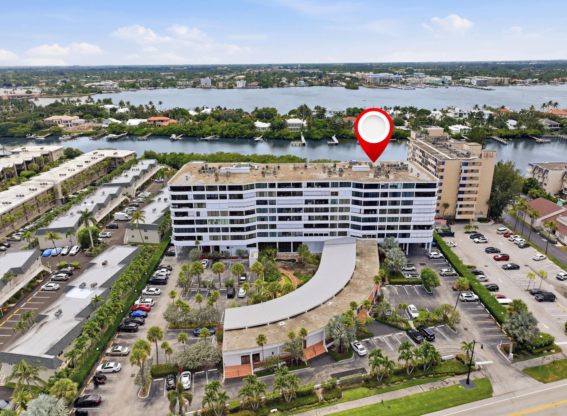 3589 S Ocean Boulevard, #808, South Palm Beach, FL 33480 Waterfront high-rise building featuring multiple levels of balconies, extensive on-site parking, a curved entry drive, and mature landscaping