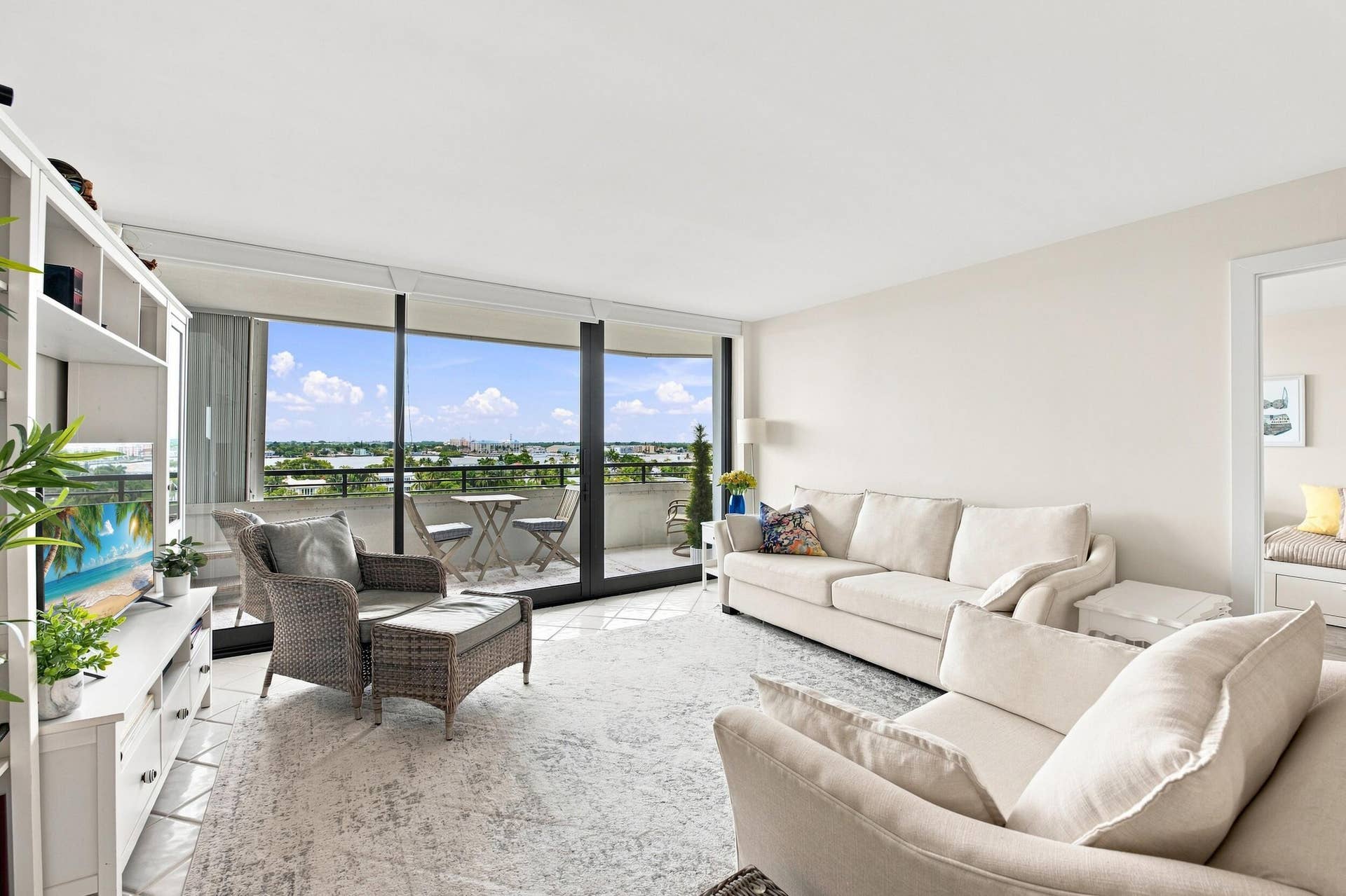 3589 S Ocean Boulevard, #808, South Palm Beach, FL 33480 Spacious living area featuring floor-to-ceiling windows, a private balcony with water and city views, and light-toned tile flooring