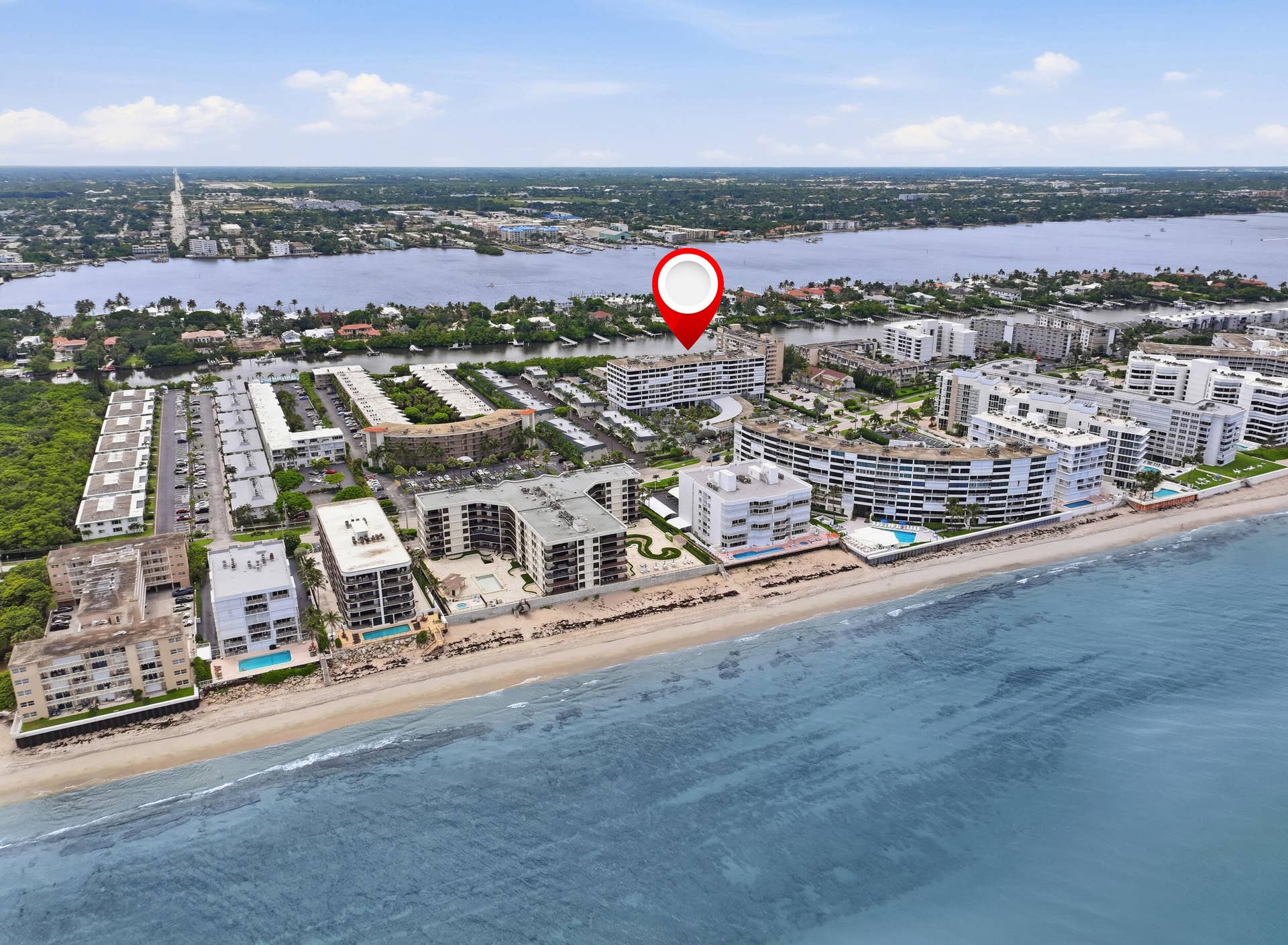 3589 S Ocean Boulevard, #808, South Palm Beach, FL 33480 Coastal multi-story building situated on a sandy beachfront with surrounding residential structures and waterfront access