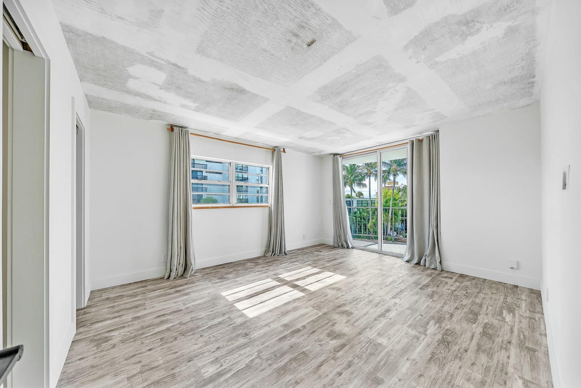 3051 NE 48TH Street, #301, Fort Lauderdale, Fort Lauderdale, FL 33308 Spacious room featuring wood-finish flooring, white walls, and a large sliding glass door opening to a balcony