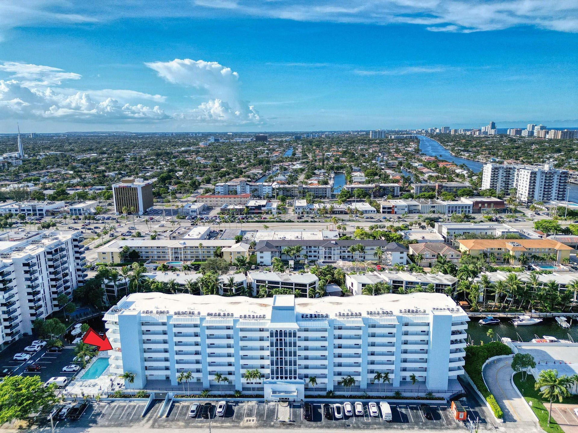 3051 NE 48TH Street, #301, Fort Lauderdale, Fort Lauderdale, FL 33308 Multi-story building featuring multiple balconies, ground-level parking, and a swimming pool with surrounding deck