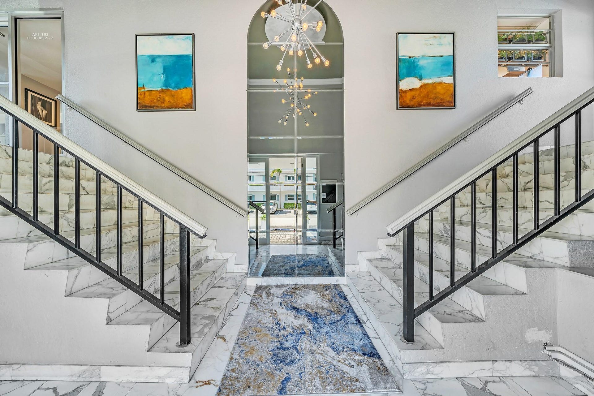 3051 NE 48TH Street, #301, Fort Lauderdale, Fort Lauderdale, FL 33308 Grand entryway featuring dual staircases, marble-finish flooring, a modern chandelier, an arched ceiling, and abundant natural light