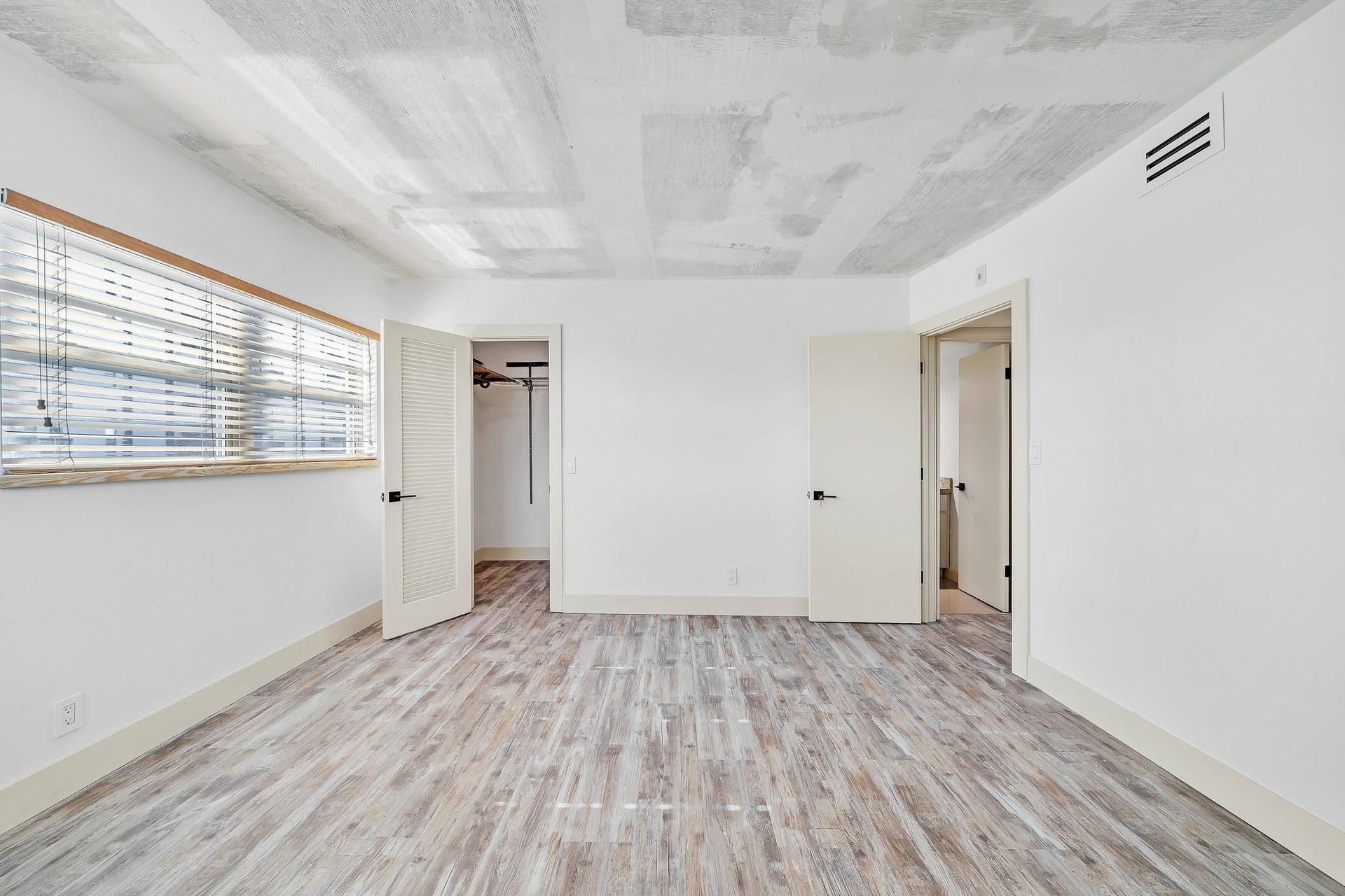 3051 NE 48TH Street, #301, Fort Lauderdale, Fort Lauderdale, FL 33308 Wood-finish flooring, white walls, louvered closet door, window with horizontal blinds, and exposed concrete ceiling