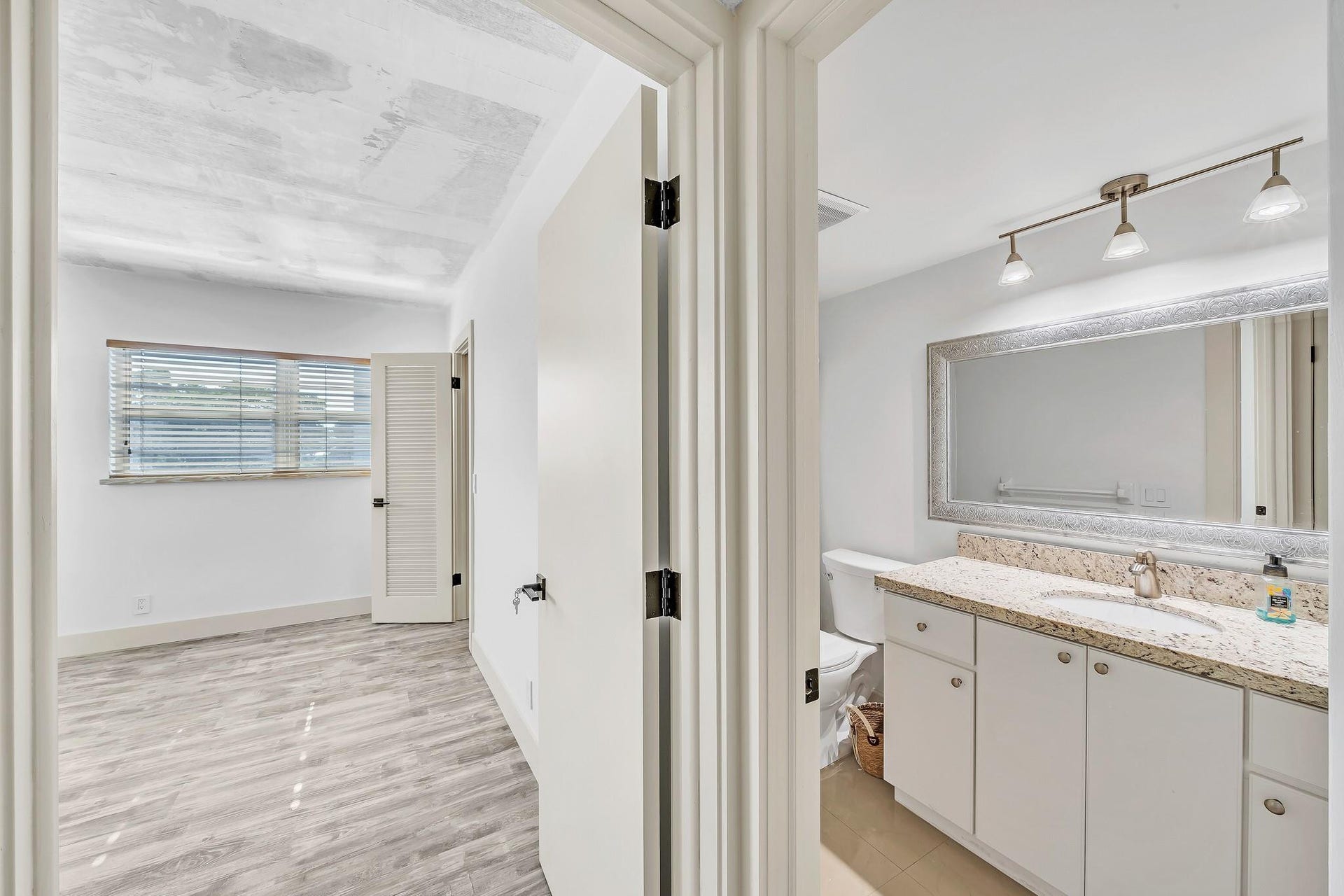 3051 NE 48TH Street, #301, Fort Lauderdale, Fort Lauderdale, FL 33308 Bathroom vanity with a light-colored countertop, white cabinetry, and a large framed mirror