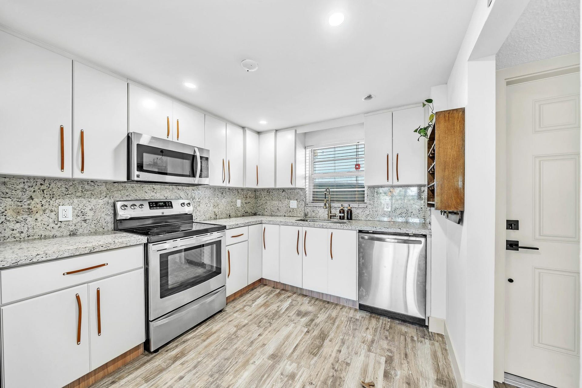 3051 NE 48TH Street, #301, Fort Lauderdale, Fort Lauderdale, FL 33308 Updated kitchen with white cabinetry, stainless steel appliances, speckled countertops, and wood-finish flooring