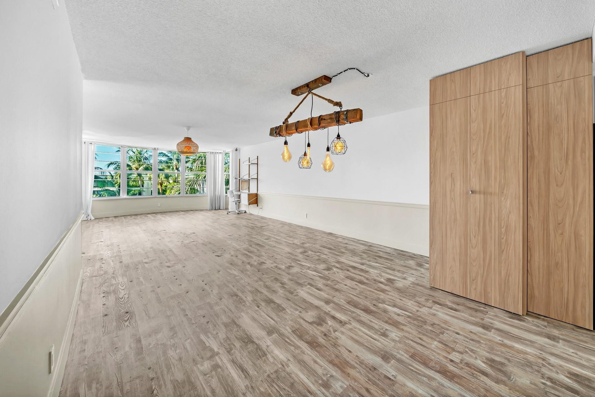 3051 NE 48TH Street, #301, Fort Lauderdale, Fort Lauderdale, FL 33308 Wood-finish flooring throughout, featuring a natural wood beam chandelier and a large picture window with outdoor scenery