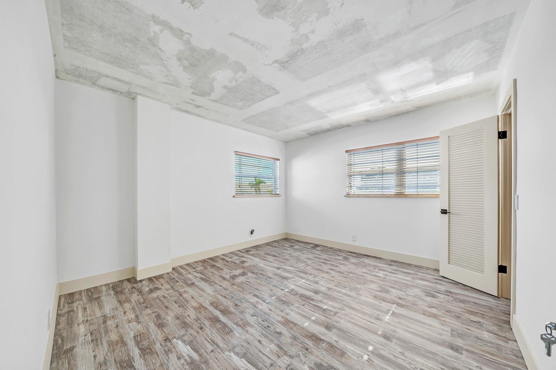 3051 NE 48TH Street, #301, Fort Lauderdale, Fort Lauderdale, FL 33308 Concrete ceiling, wood-finish flooring, two windows with blinds, louvered door, white walls