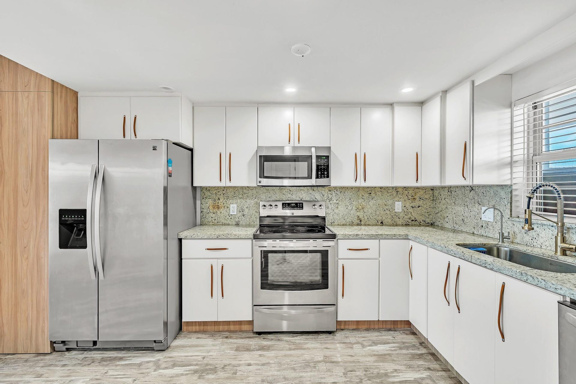 3051 NE 48TH Street, #301, Fort Lauderdale, Fort Lauderdale, FL 33308 Kitchen featuring white cabinetry, stainless steel appliances, speckled countertops, and a full-height backsplash