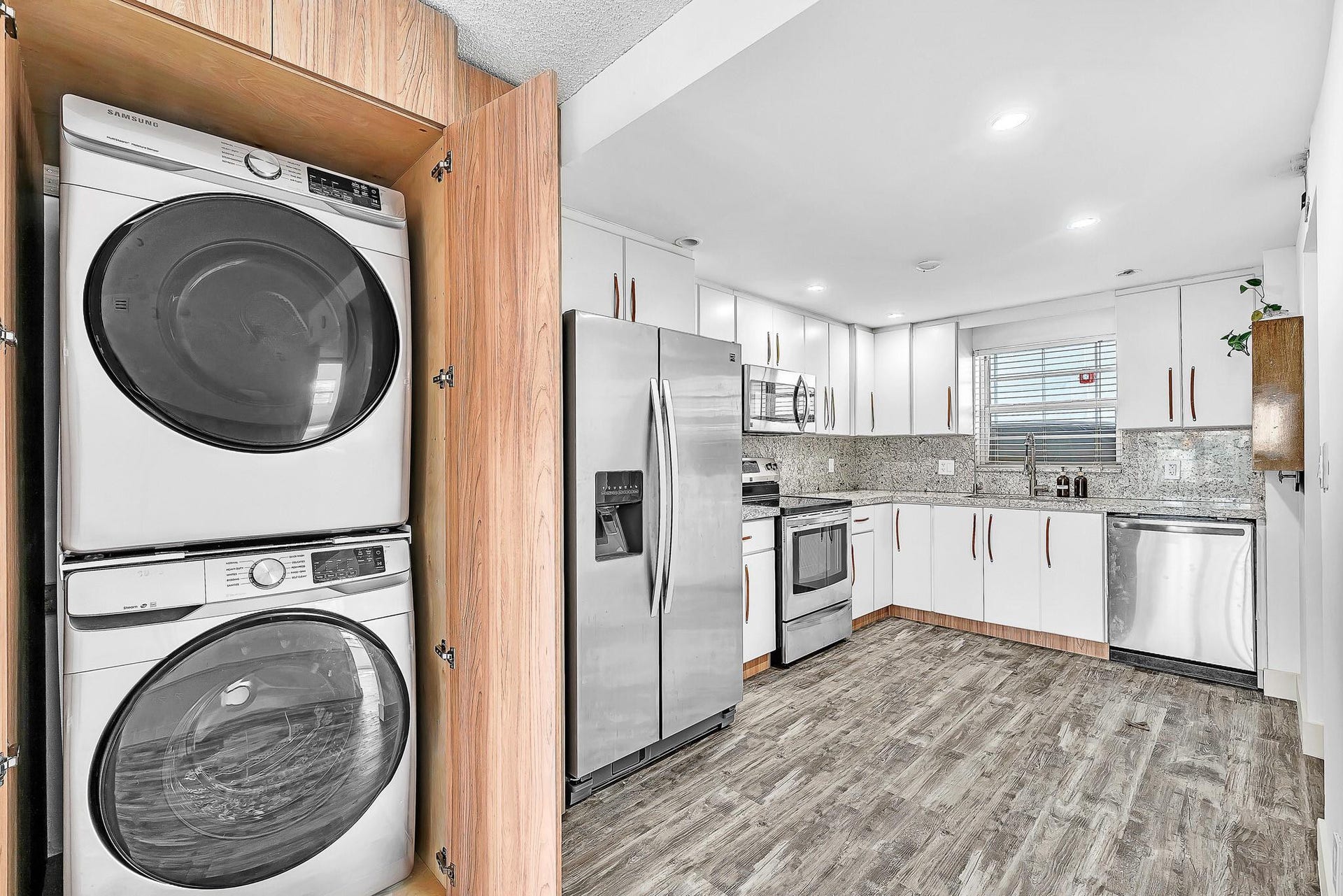 3051 NE 48TH Street, #301, Fort Lauderdale, Fort Lauderdale, FL 33308 White cabinetry with coordinating hardware, stainless steel appliances, wood-finish flooring, and a stacked washer and dryer