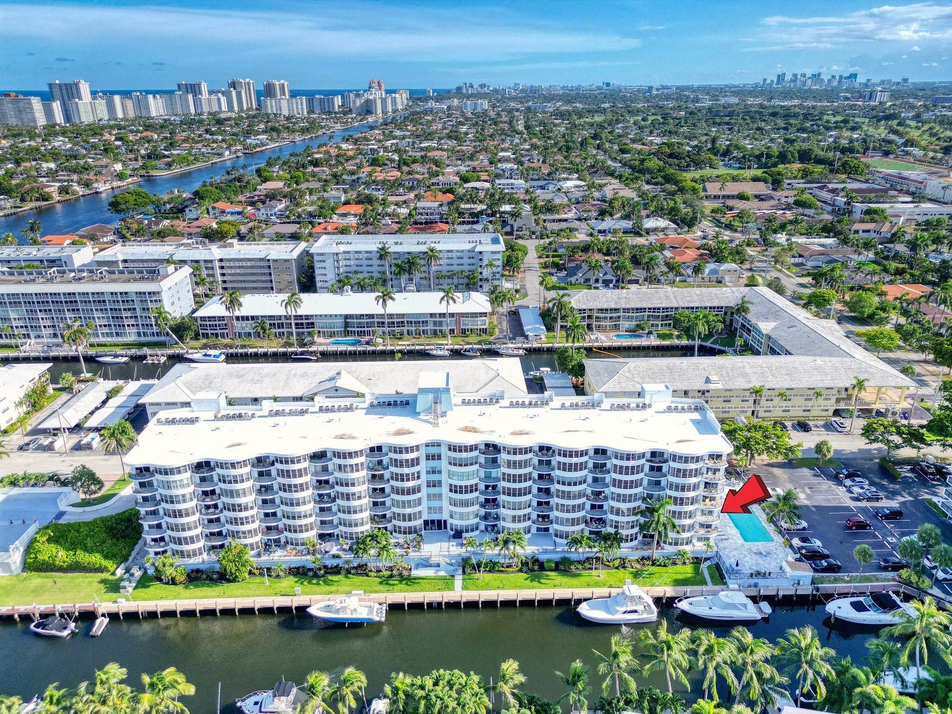 3051 NE 48TH Street, #301, Fort Lauderdale, Fort Lauderdale, FL 33308 Multi-story building featuring multiple balconies, waterfront access, a dedicated parking area, and an outdoor swimming pool