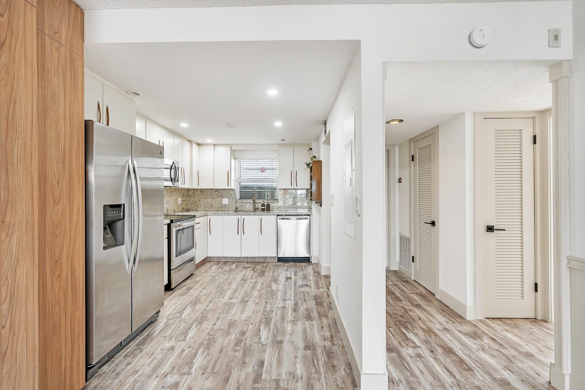 3051 NE 48TH Street, #301, Fort Lauderdale, Fort Lauderdale, FL 33308 Kitchen featuring white cabinetry, stainless steel appliances, granite countertops, and wood-finish flooring