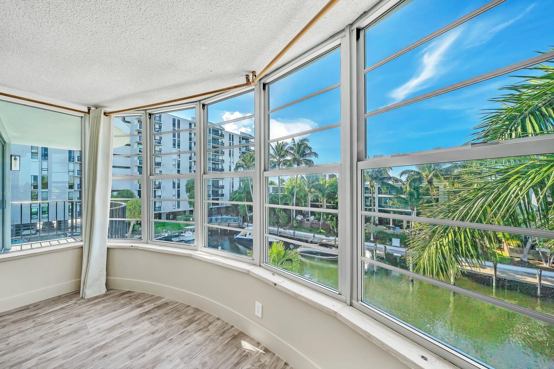 3051 NE 48TH Street, #301, Fort Lauderdale, Fort Lauderdale, FL 33308 Curved bay window with wood-finish flooring, textured ceilings, and a partial balcony