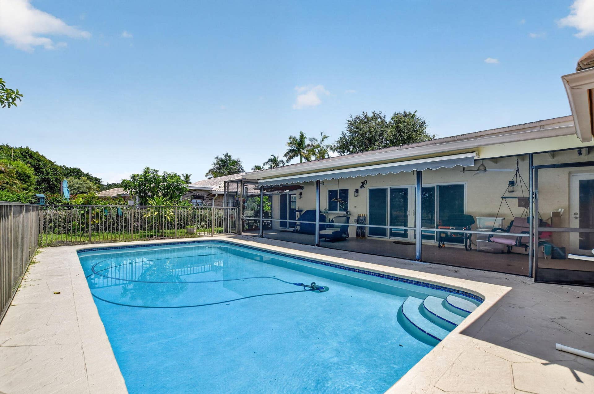 Rectangular swimming pool with integrated steps, screened patio, and a retractable awning