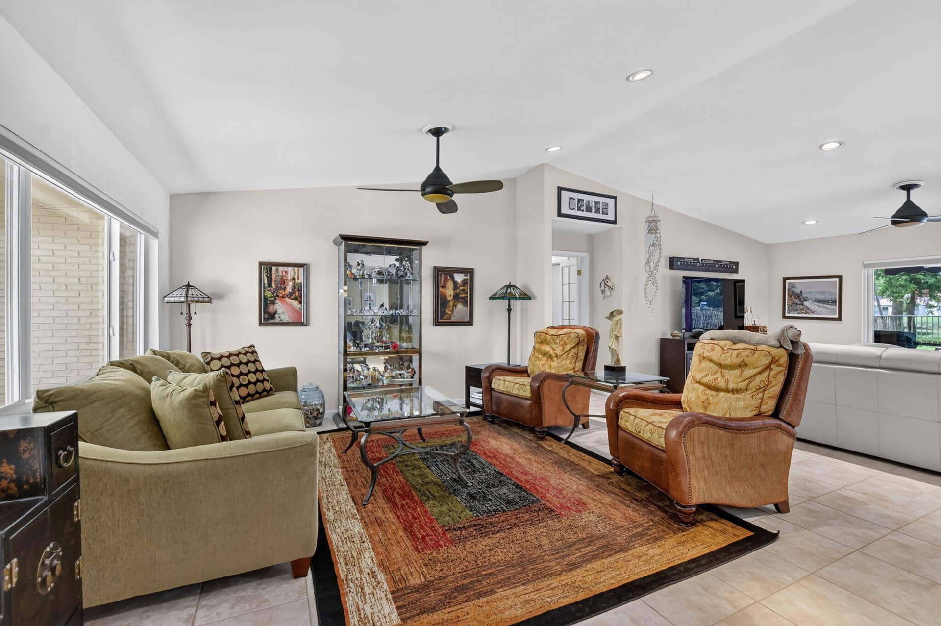 Spacious room featuring vaulted ceilings, recessed lighting, tile flooring, and multiple ceiling fans