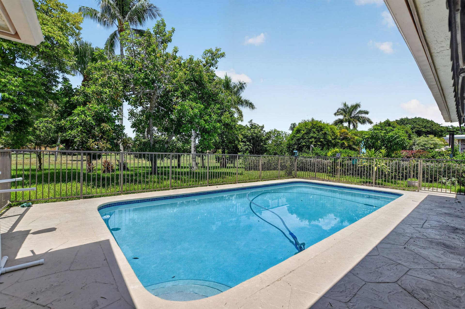 Rectangular swimming pool with a wide coping, surrounded by a stamped concrete patio