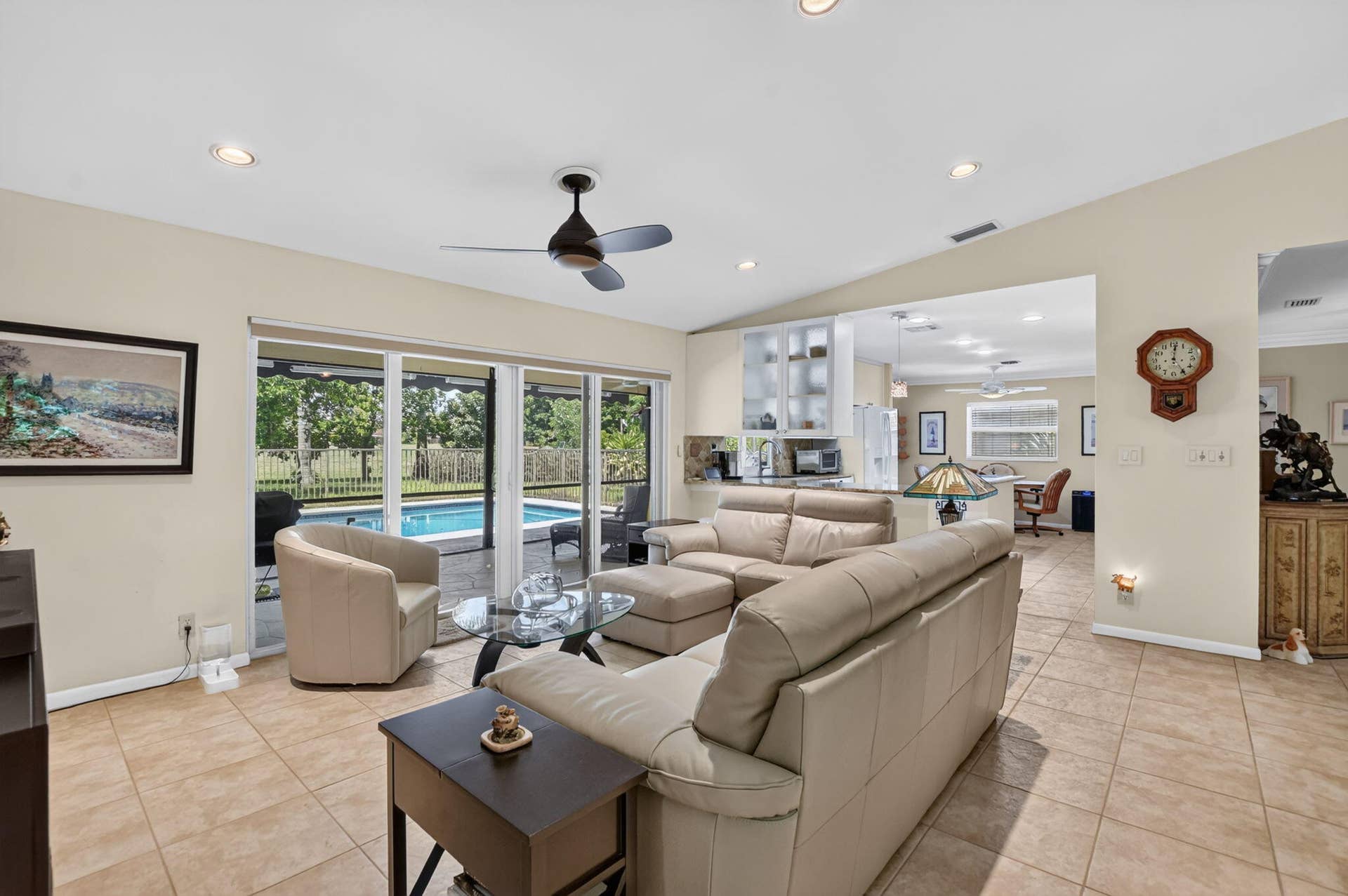Spacious living area featuring neutral-toned tile flooring, recessed lighting, and a ceiling fan