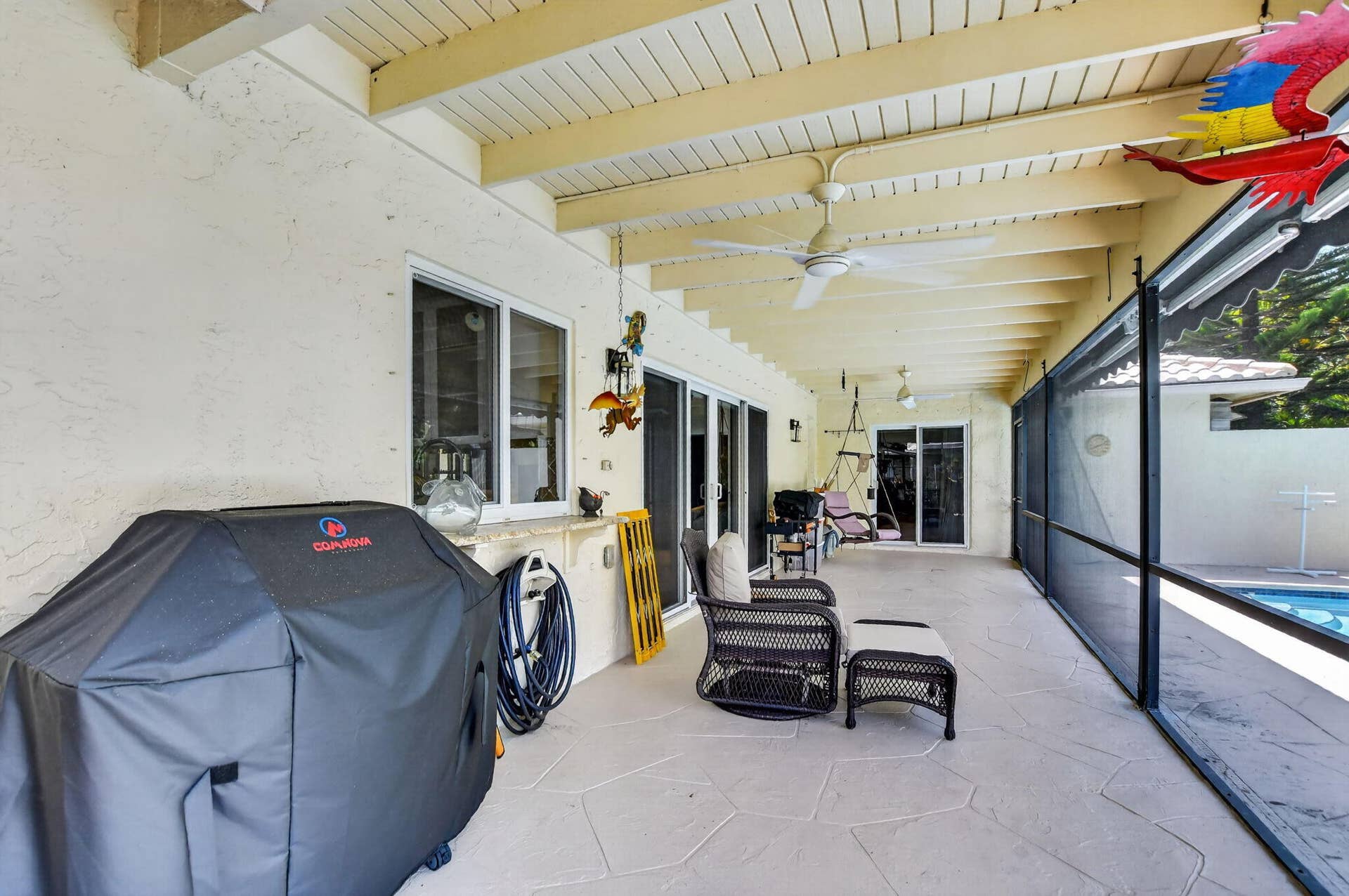 Expansive covered patio with a textured concrete floor, screened enclosure, and ceiling fans